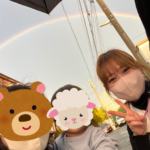 虹を背景に利用者の家族と写真を撮る看護師